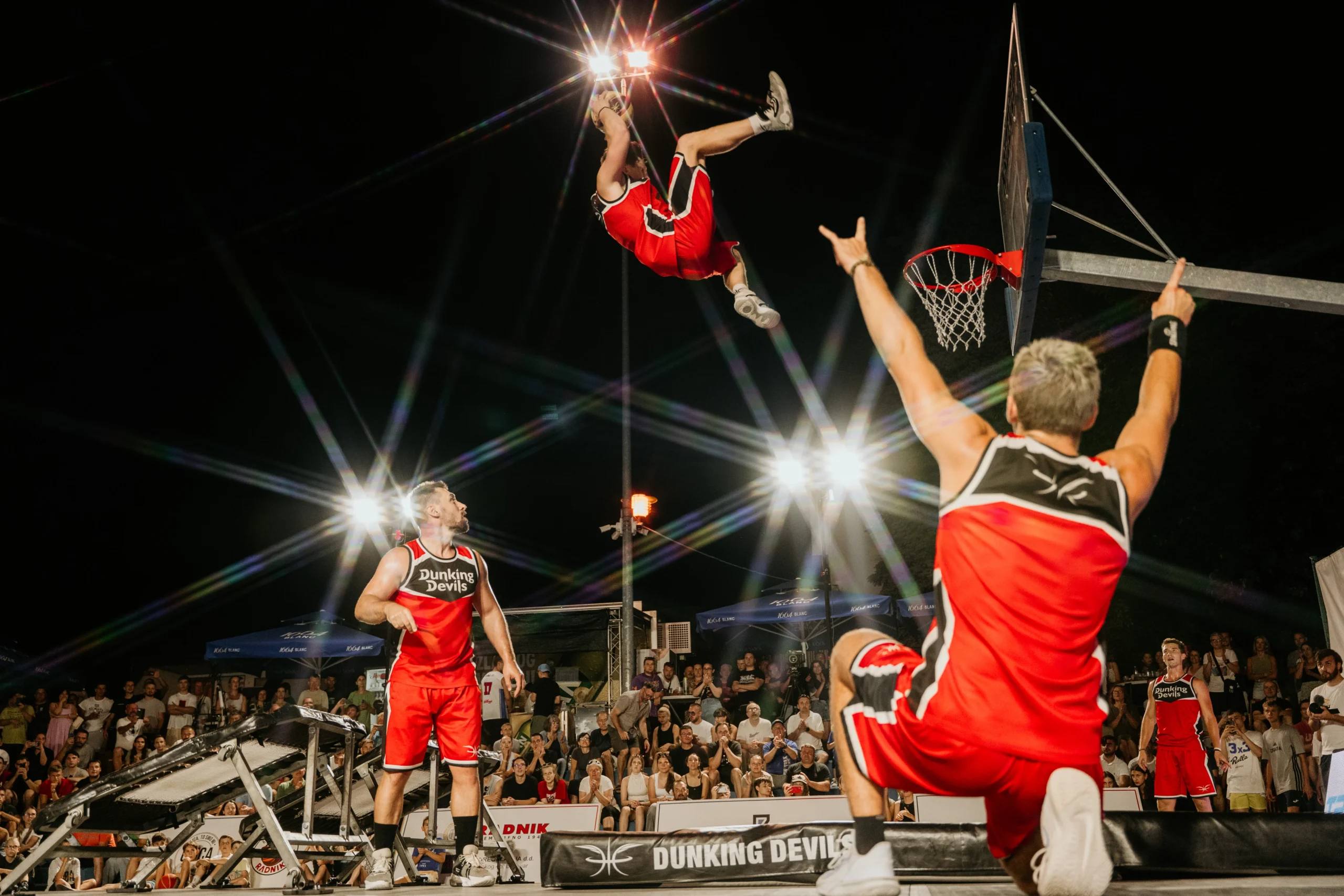 Dunking Devils athlete mid-air above a crowd at an outdoor show.