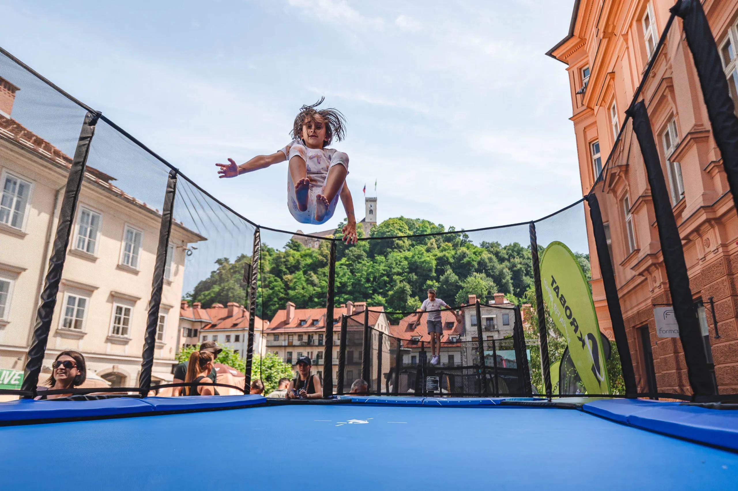 A young girl jumps high on a netted trampoline in Ljubljana’s old town.