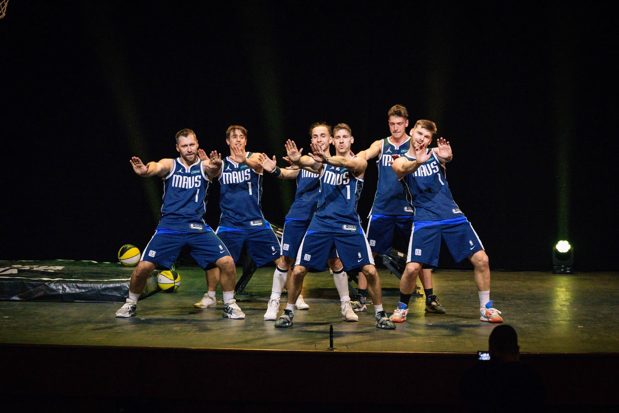 The Dunking Devils cast in blue jerseys posing on stage.