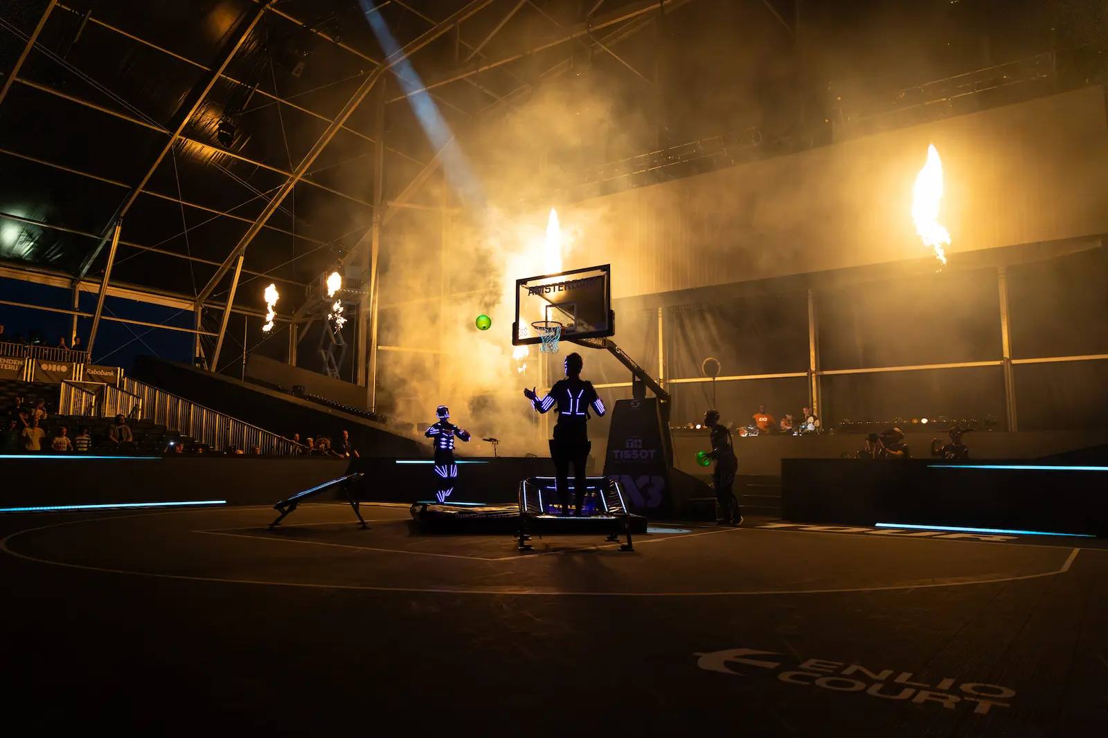 LED performers on court in smoke and flames as a glowing ball flies towards the hoop at FIBA 3x3 Amsterdam.