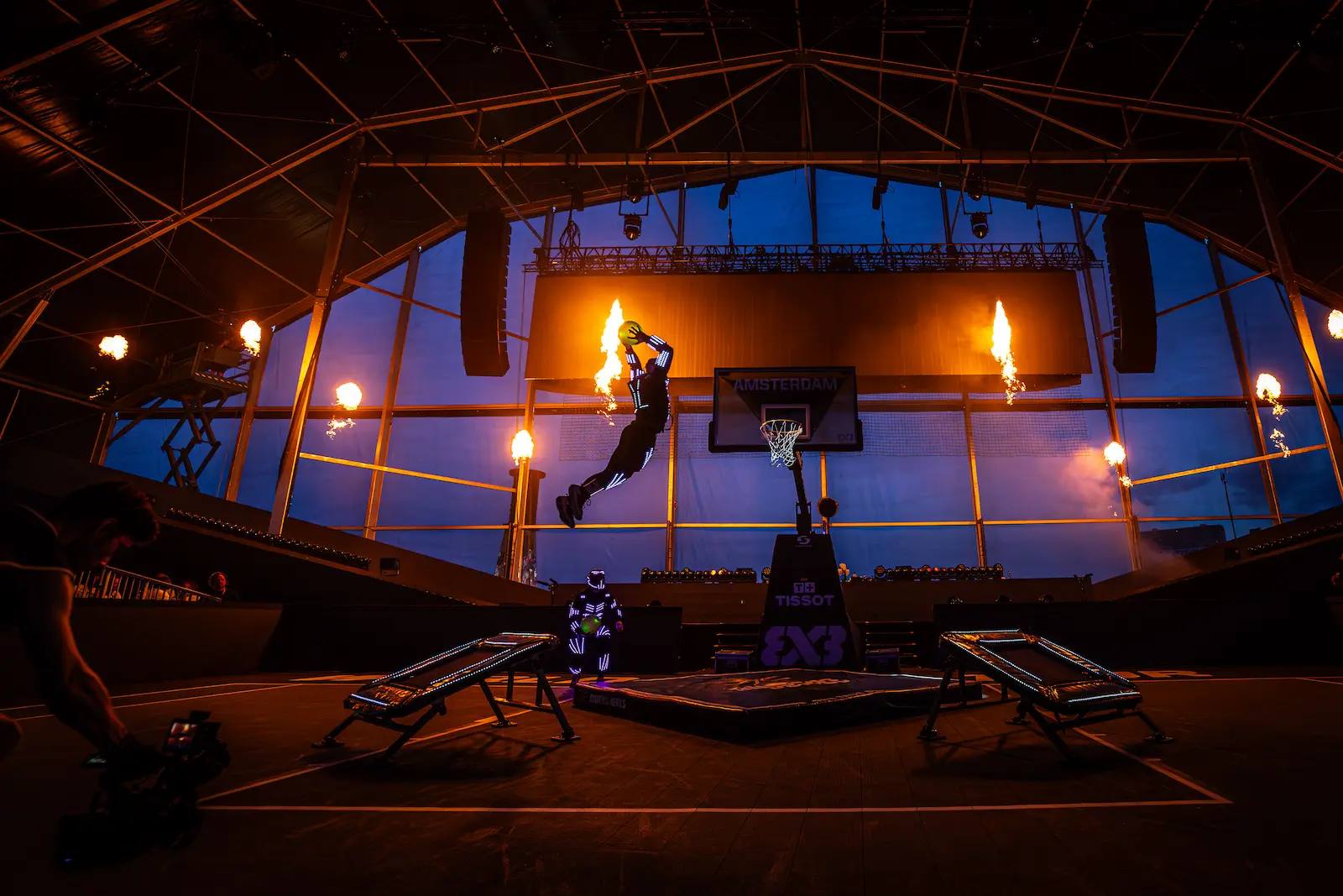 LED-suited Dunking Devils athlete flying to dunk between pyro flames at FIBA 3x3 Amsterdam.